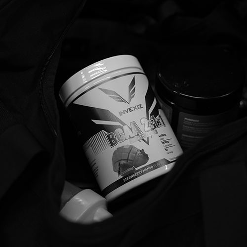 invexiz-bcaa-2-1-1-l-glutamine-strawberry-mango-supplement-sporttas Pot INVEXIZ BCAA 2:1:1 met L-Glutamine in de smaak Strawberry Mango, samen met andere sportsupplementen en een shaker in een zwarte sporttas.